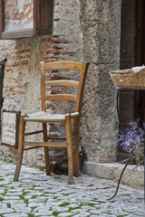 Fototapeta na wymiar vecchia sedia di paglia davanti a casa in pietra