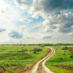 Fototapeta na wymiar road in green meadow and dramatic cloudy sky