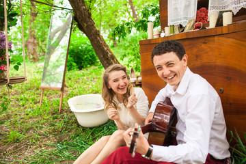 Young couple laughs while sitting on the ground in green garden