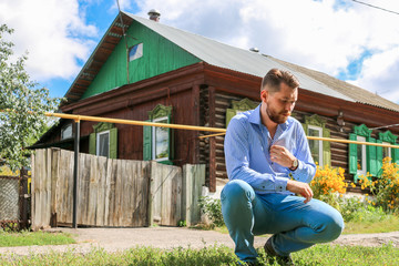 Russian stylish man with a beard and an old house in the background