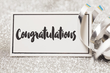 Congratulations card on a silver glitter background with paper streamers
