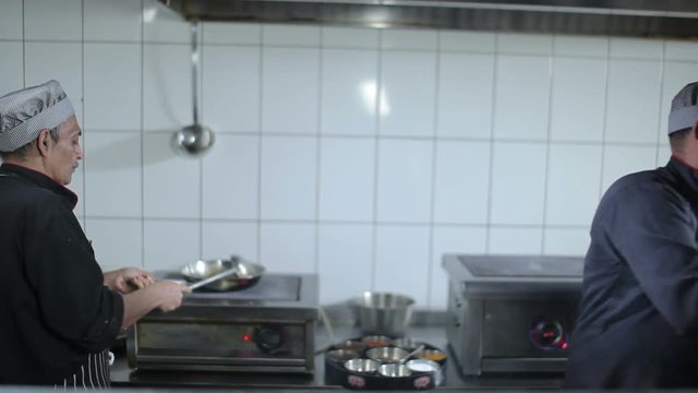 Two cooks are preparing the dishes at the kitchen