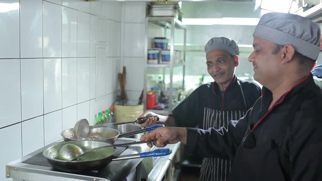 Two cooks cooking dishes at kitchen restaurant