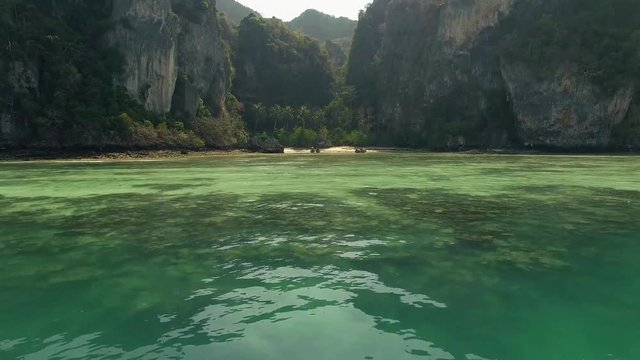 The drone travels on the water to the beach in Thailand.