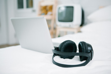 Obraz na płótnie Canvas Black Headphones on the bed and laptop computer