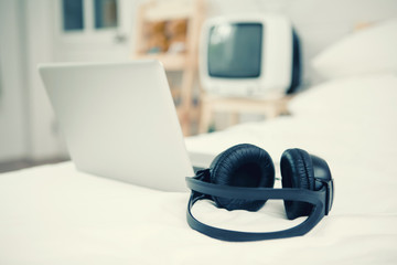 Black Headphones on the bed and laptop computer