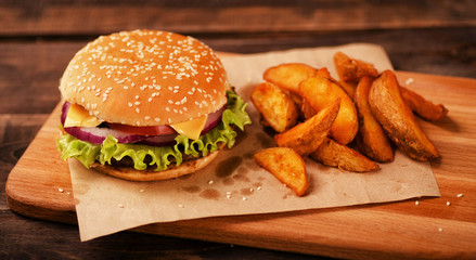 Burger with cheese, lettuce and vegetables, with potato wedges