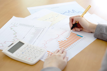 Close-up Of Businesswoman Analyzing Graph With Calculator At Des