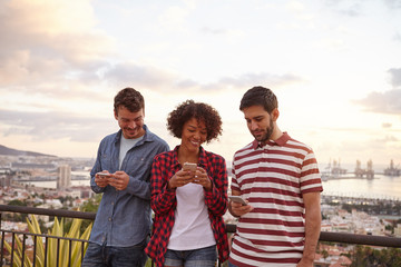 Two guys and a girl looking at cellphones