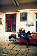 Woman in blue sweater sits before the wall with old paintings