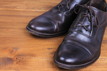 Leather shoes winter care. Stylish male boots on wooden background