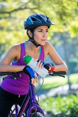 Fototapeta na wymiar Female athletic leaning on bicycle in countryside
