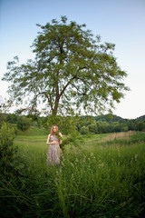 Look from afar at woman standing under green tree