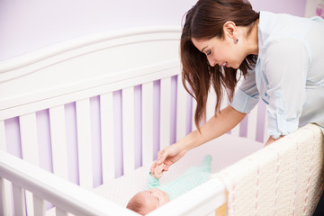 Mother playing with her baby in a crib