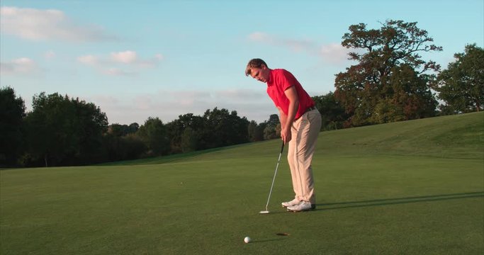 Golfer misses putt and throws club down in disbelief.