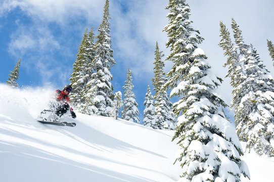 A woman skiiing in blue skies and powder at Whitewater Winter Resort, Nelson, British Columbia