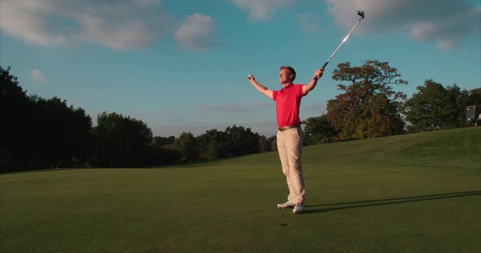 Golfer retrieves ball from cup and celebrates