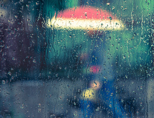 man under an red umbrella in the rain. waterdrops on glass