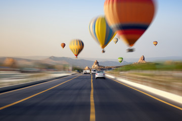 Hot air balloons flies above road on sunrise in Kapadokya, Turke