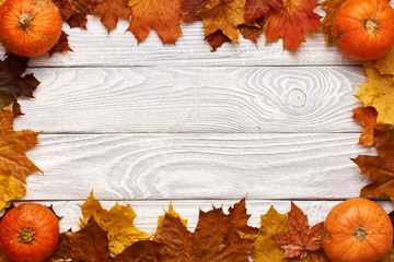 Autumn leaves and pumpkins over old wooden background