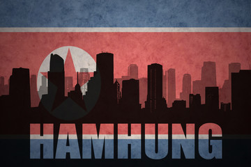 abstract silhouette of the city with text Hamhung at the vintage north korea flag background © luzitanija