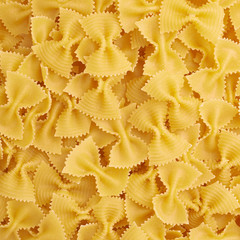 Pile of farfalle yellow pasta as abstract background