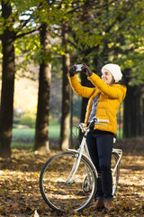 Young girl on bike taking photos with cell phone outdoor
