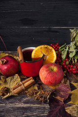 red cup of hot mulled wine in autumn among leaves