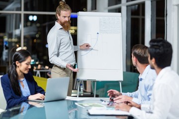 Businessman discussing graph on white board with colleagues