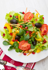 mixed salad with tomatoes in white plate on wood table