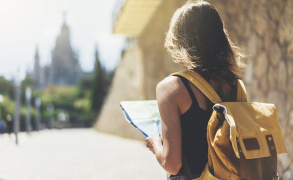 Hipster young girl with backpack using and looking at map. Said view tourist traveler enjoying on background panoramic city. Person visiting the sights Barcelona in holiday. Mockup for text message