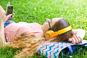 Beautiful girl relaxing and listen music in the headphones in th
