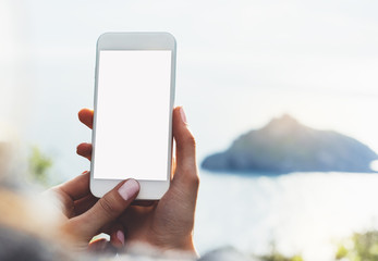 Hipster girl texting message on blank mobile close up, view tourist hands using gadget phone on device travel on background green mountains landscape; finger touch screen cellphone mockup nature