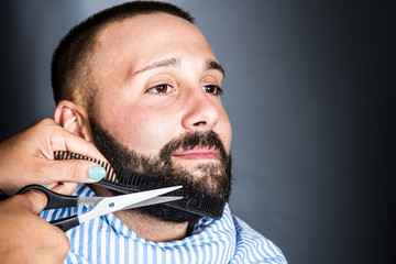 woman is trimming the beard of a young man