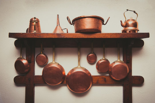 Vintage copper cookware collection on wooden shelf