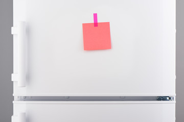 Blank pink paper note and pink sticker on white refrigerator