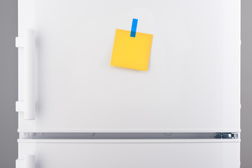 Blank yellow paper note and blue sticker on white refrigerator © IntelWond
