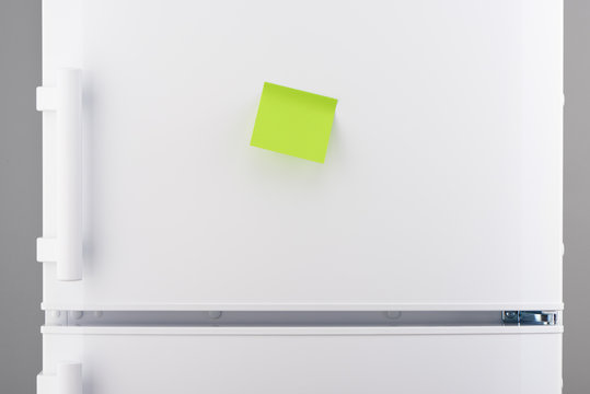 Blank green sticky paper note on white refrigerator