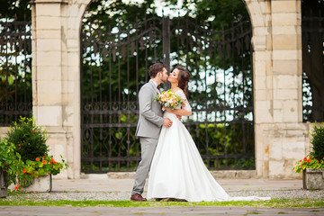 Obraz premium Bride and groom in a park kissing.couple newlyweds bride and groom at a wedding in nature green forest are kissing photo portrait.Wedding Couple