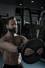 Hombre con grandes músculos levantando peso mientras entrena en el gimnasio. Ponerse en forma.