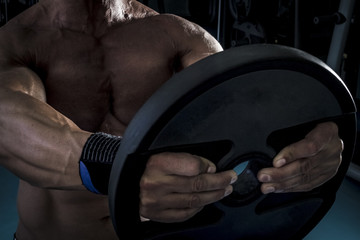 Obraz premium Hombre con grandes músculos levantando peso mientras entrena en el gimnasio. Ponerse en forma.