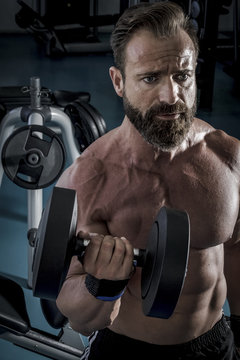 Hombre con grandes músculos levantando peso mientras entrena en el gimnasio. Ponerse en forma.