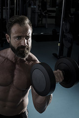 Hombre con grandes músculos levantando peso mientras entrena en el gimnasio. Ponerse en forma.