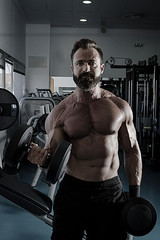 Hombre con grandes músculos levantando peso mientras entrena en el gimnasio. Ponerse en forma.