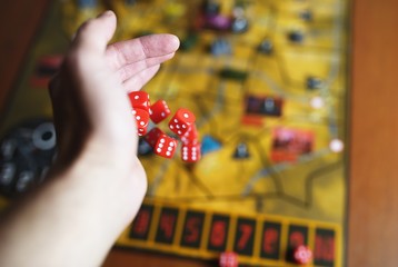 Several rolling red dice fall on a table with boardgame. Gameplay moments
