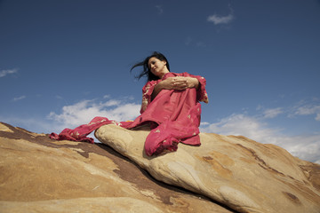 bonita mujer sentada sobre una roca y relajada