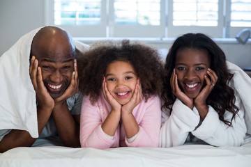 Obraz premium Family with hands on face lying on bed