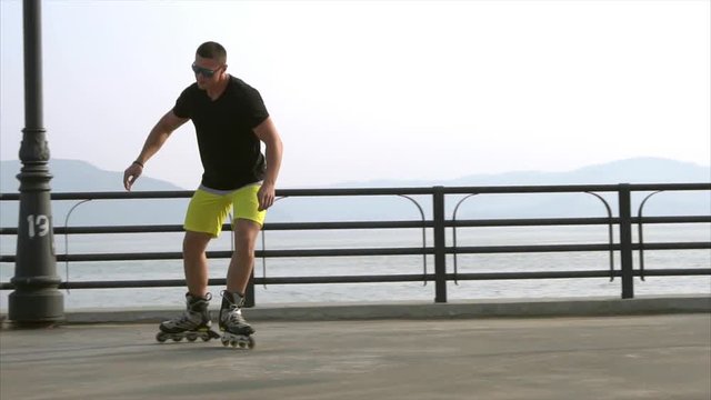 Young sporty man roller skating on summer waterfront HD