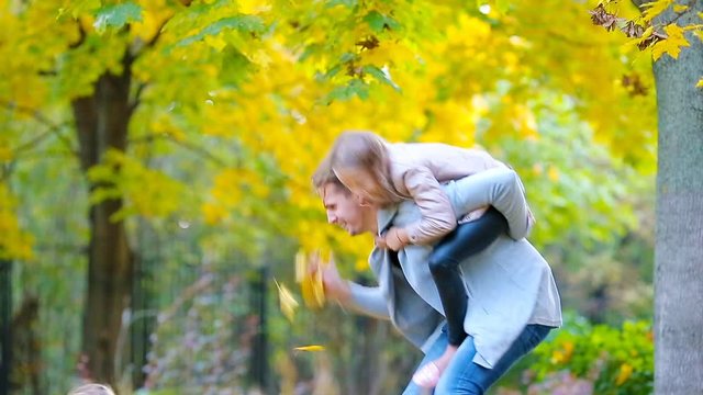 Happy family in autumn park outdoors. Happy kids ans dad throwing leaves around on an autumn day outdoors