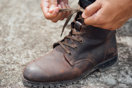 Men tying shoes, Men fashion brown leather boots. Toned picture.